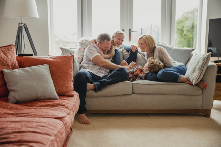 A family, two parents and two children, enjoying time together on a sofa in a bright living room