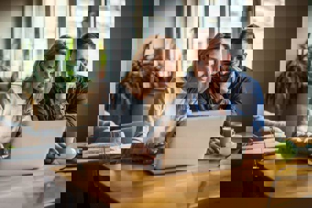 A couple reviews HVAC efficiency changes on a laptop in their home